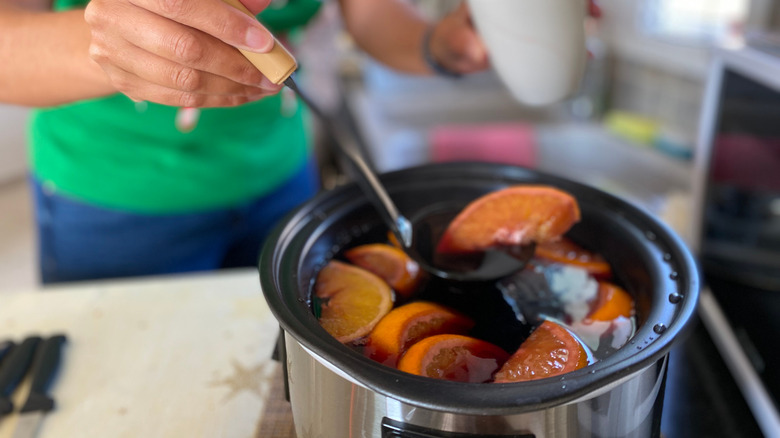 Woman serving mulled wine from slow cooker