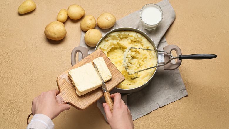 Person adding butter to mashed potatoes