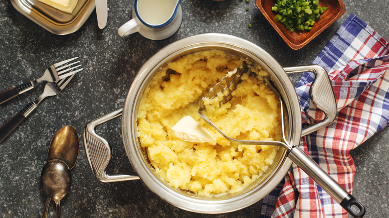 Pan of mashed potatoes and masher