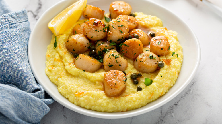 Seared scallops are displayed on a bed of grits.