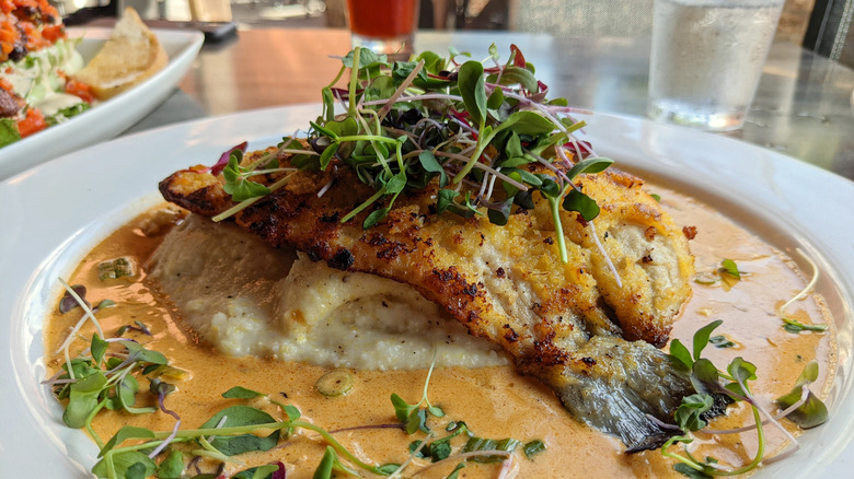 Fried trout is served on a bed of grits.