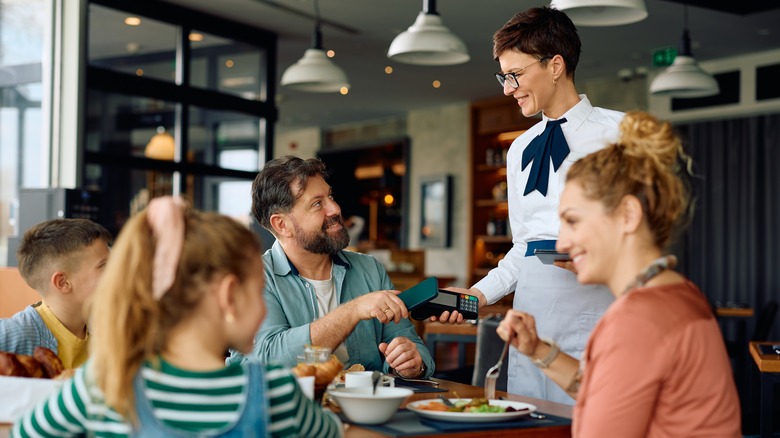 Father paying for family meal at restaurant table