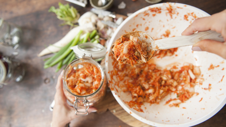 scooping kimchi from bowl to jar