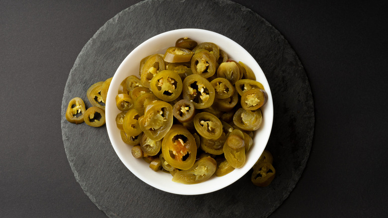 bowl of sliced pickled jalapeños on slate