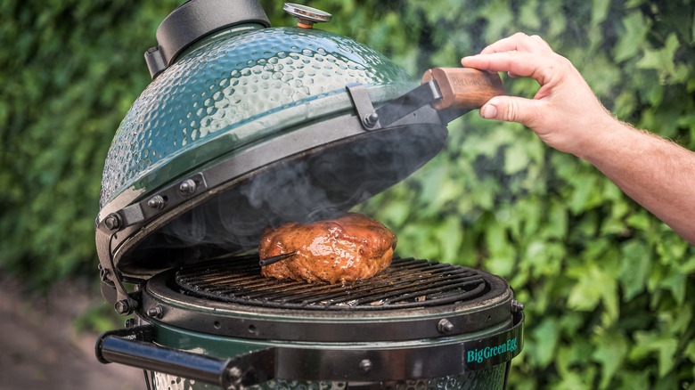 Man opening kamado grill top