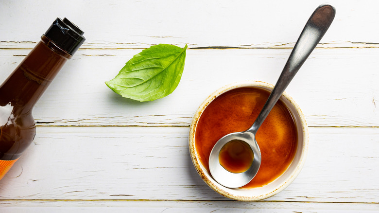 Bottle of Worcestershire sauce with bowl, spoon, and leaf