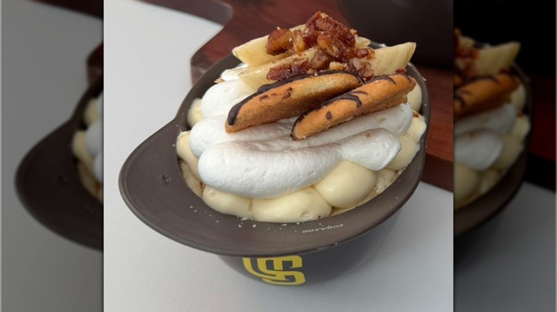 Vanilla wafers, chocolate, and banana slices with candied nuts on a bed of whipped cream and vanilla pudding in a small San Diego Padres dessert helmet shell