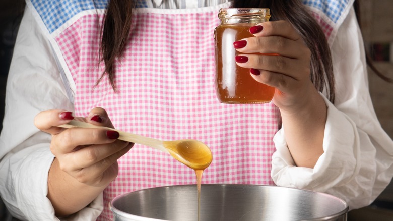 Woman adding honey to pot