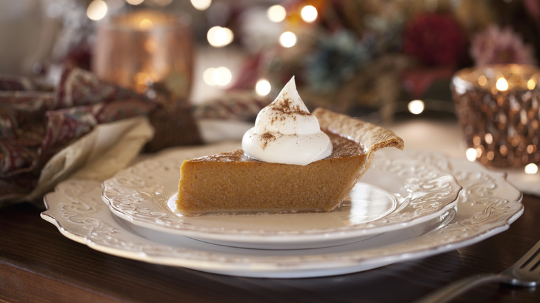 Slice of pumpkin pie at a formal place setting