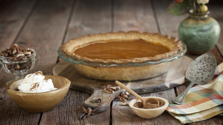 Pumpkin pie and ingredients on a wooden table