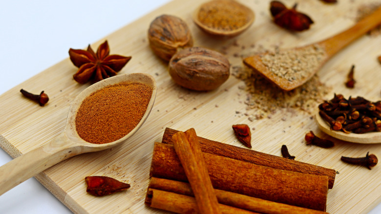 warm spices like cinnamon nutmeg, and cloves sit on a wood cutting board