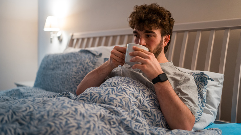 man drinking tea in bed
