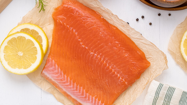 fresh, uncooked salmon fillet alongside lemon slices