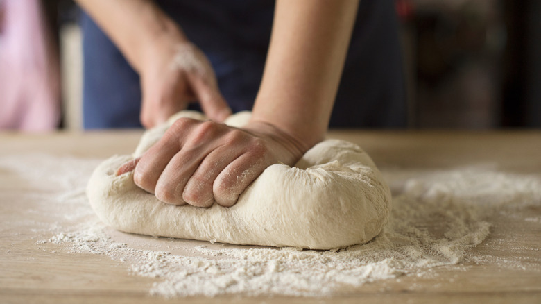 Woman's hands kneading dough on wooden surface