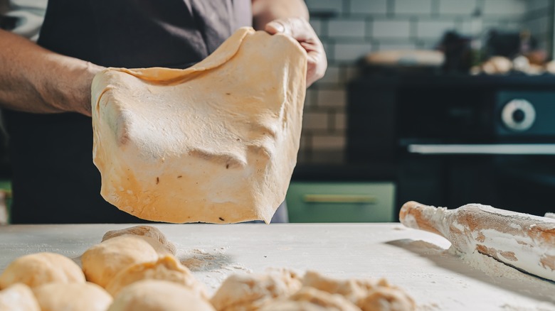 Man working thin pizza dough