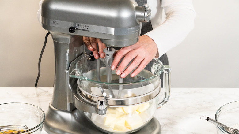 Someone setting up a gray KitchenAid-esq stand mixer
