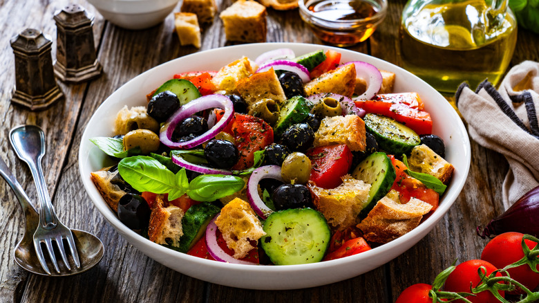 Panzanella salad in bowl with ingredients around it