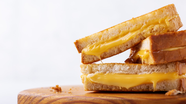 A stack of grilled cheese sandwiches on wooden board