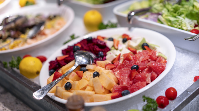 white plate with cantaloupe, watermelon, dragon fruit, and blueberries on ice