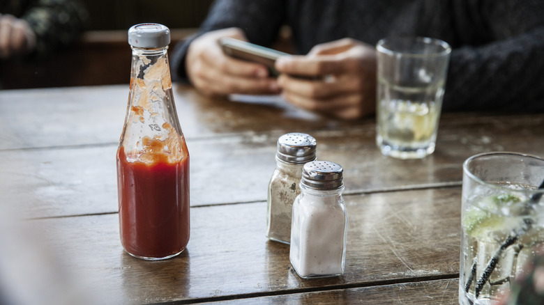 ketchup bottle and salt and pepper shakers on wooden table