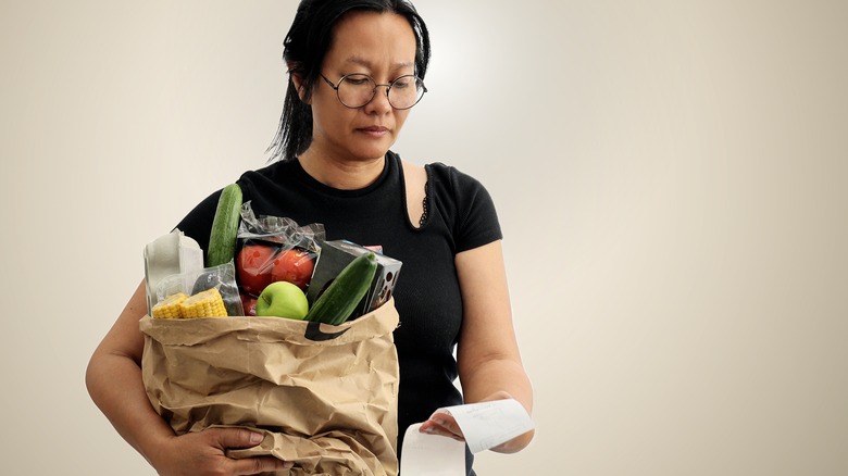 Woman examining groceries receipt