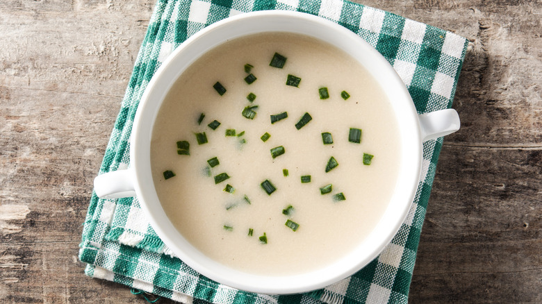 A bowl of potato soup with chives scattered on top