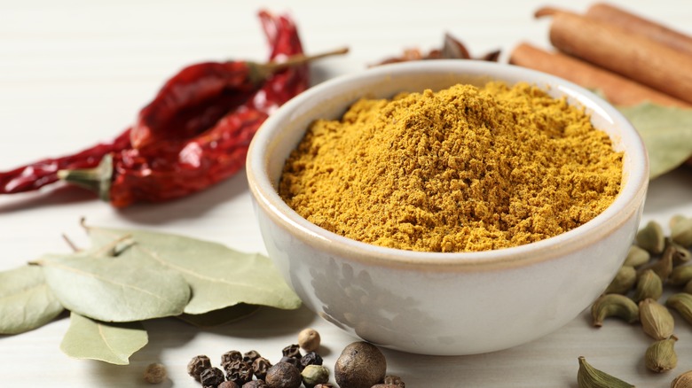 A bowl of curry powder surrounded by other seasonings