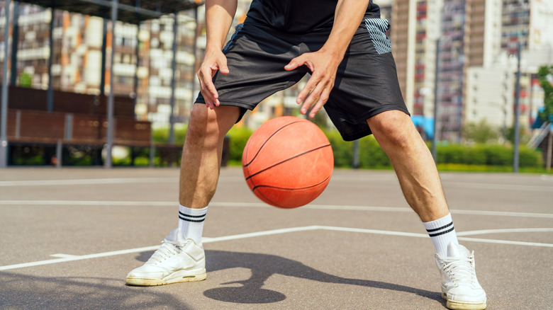 Man dribbling ball on outdoor basketball court