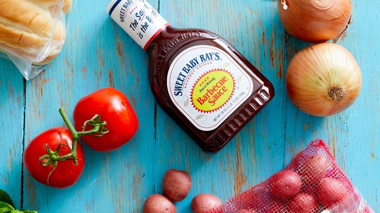 Bottle of Sweet Baby Ray's BBQ sauce surrounded by fresh produce