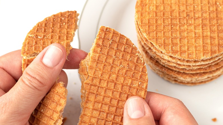 Person breaking a stroopwafel in half