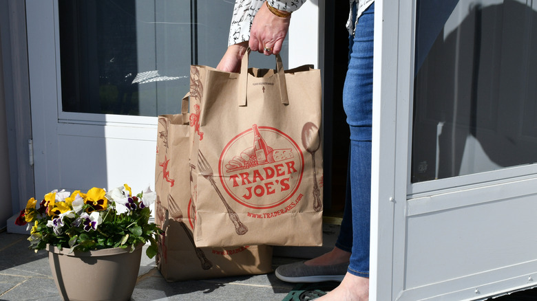 Woman picking up two Trader Joe's paper bags