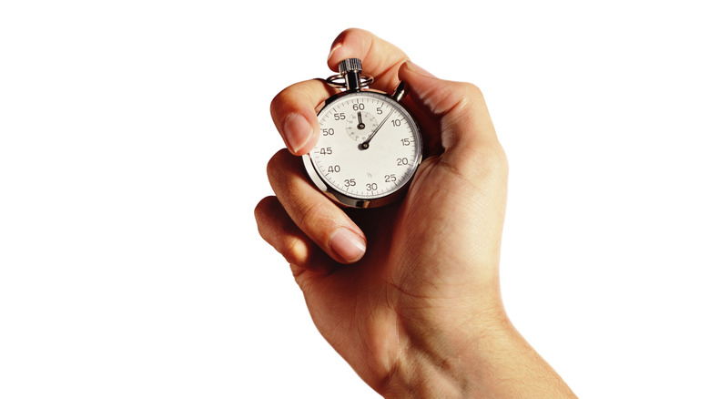 upraised hand holding stopwatch timer