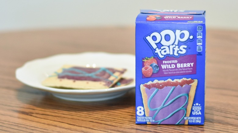 A box of Wild Berry Pop Tarts on a wooden table in front of a plate