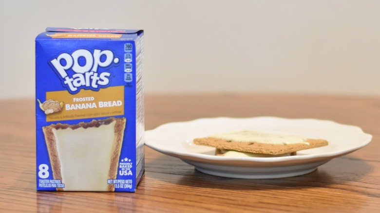 A box of Banana Bread Pop Tarts on a wooden table next to a plate