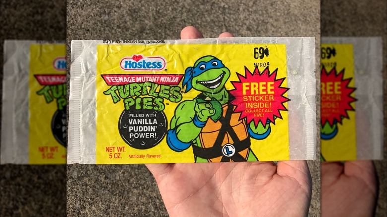 A person holding an empty wrapper of Hostess Teenage Mutant Ninja Turtle Pie