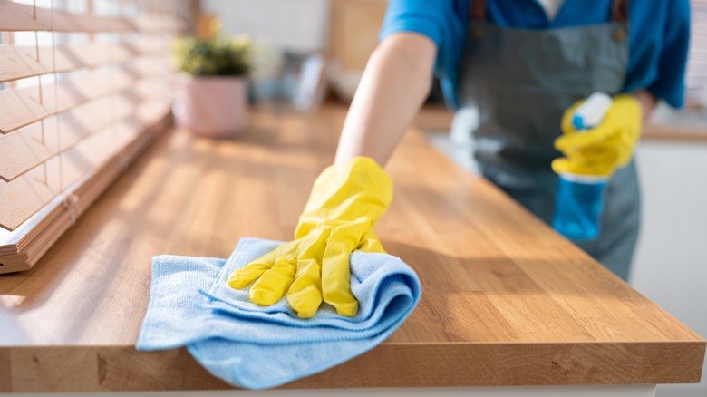 Person wearing rubber gloves, cleaning kitchen counter top