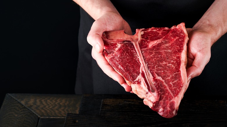 Person holding a T-bone steak