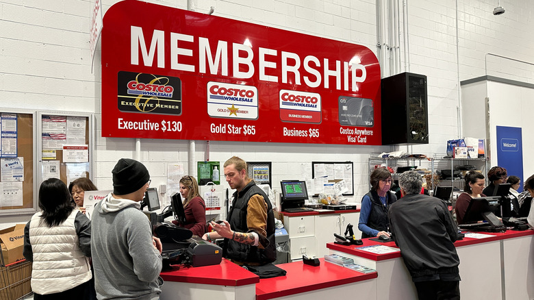 People stand at the membership counter at Costco talking to employees behind a red counter