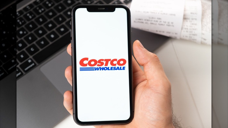 Hand holding smartphone with Costco logo