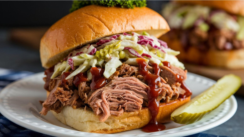 A pulled pork sandwich with coleslaw and a pickle