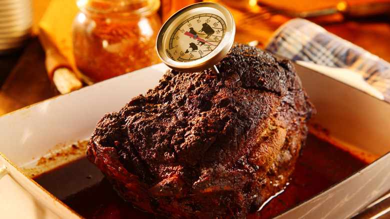 A cooked pork shoulder with a meat thermometer