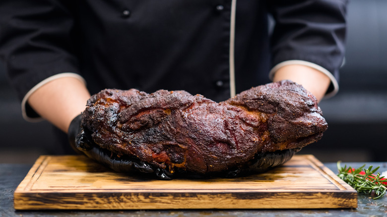 A smoked pork shoulder resting on a cutting board