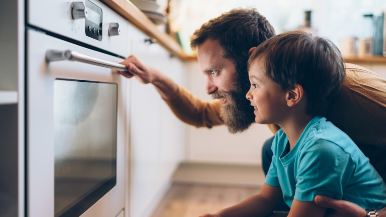 Man and child looking into oven