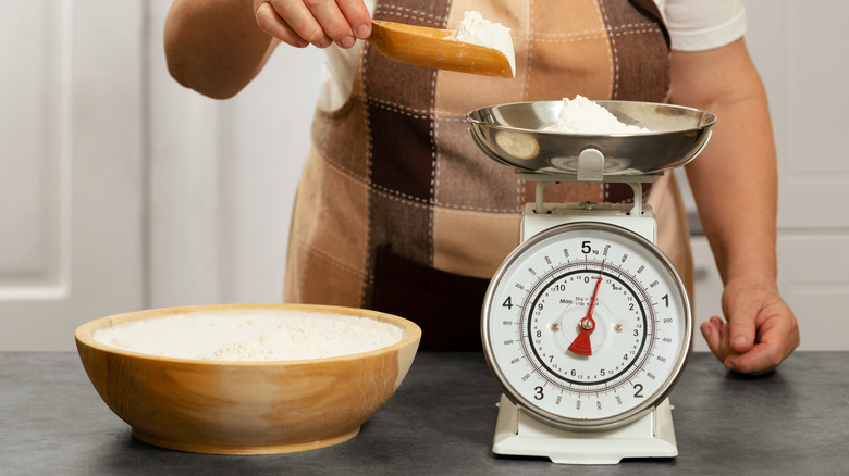 Person weighing flour on scale