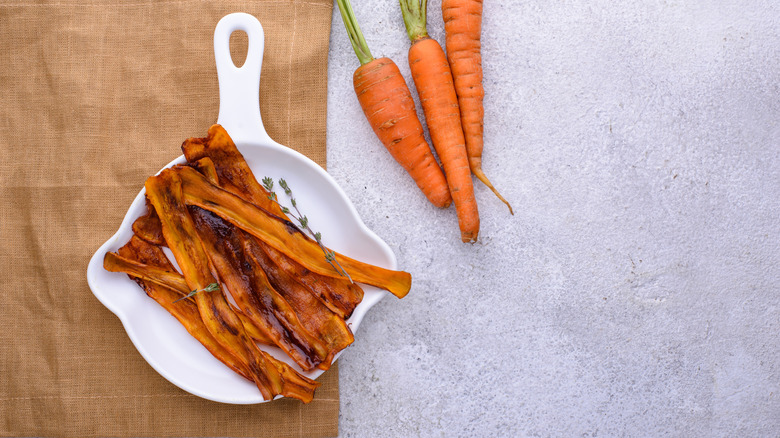 Strips of carrot bacon in a white bowl