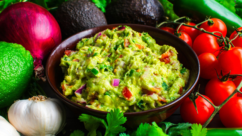 Bowl of homemade guacamole with the ingredients around the outside