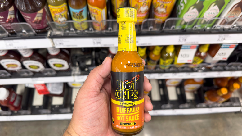 Person holding a hot sauce bottle in a store