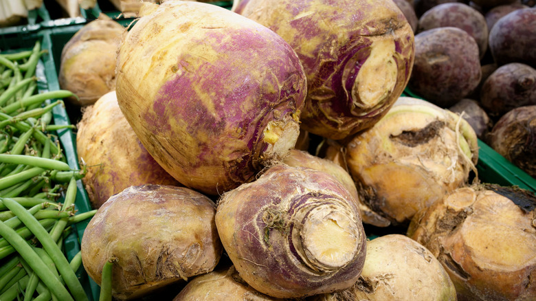 Raw rutabaga sit in a stack on display at an outdoor market