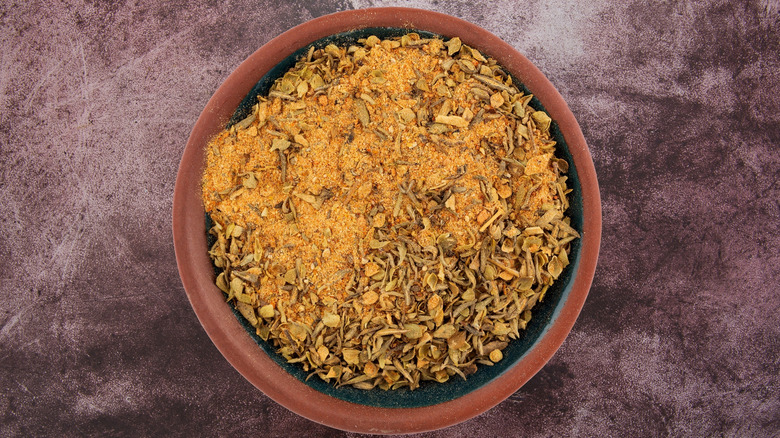 An overhead view of a red bowl with blackening seasoning on a dark gray background