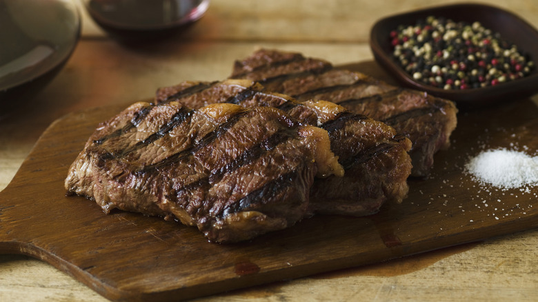 cooked steaks with grill marks resting on a cutting board